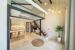 Un interior moderno con cocina, comedor y una escalera que sube a un nivel superior.