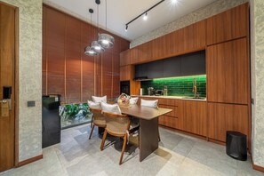 Une cuisine moderne avec des meubles en bois, une table à manger avec des chaises et un revêtement mural vert.