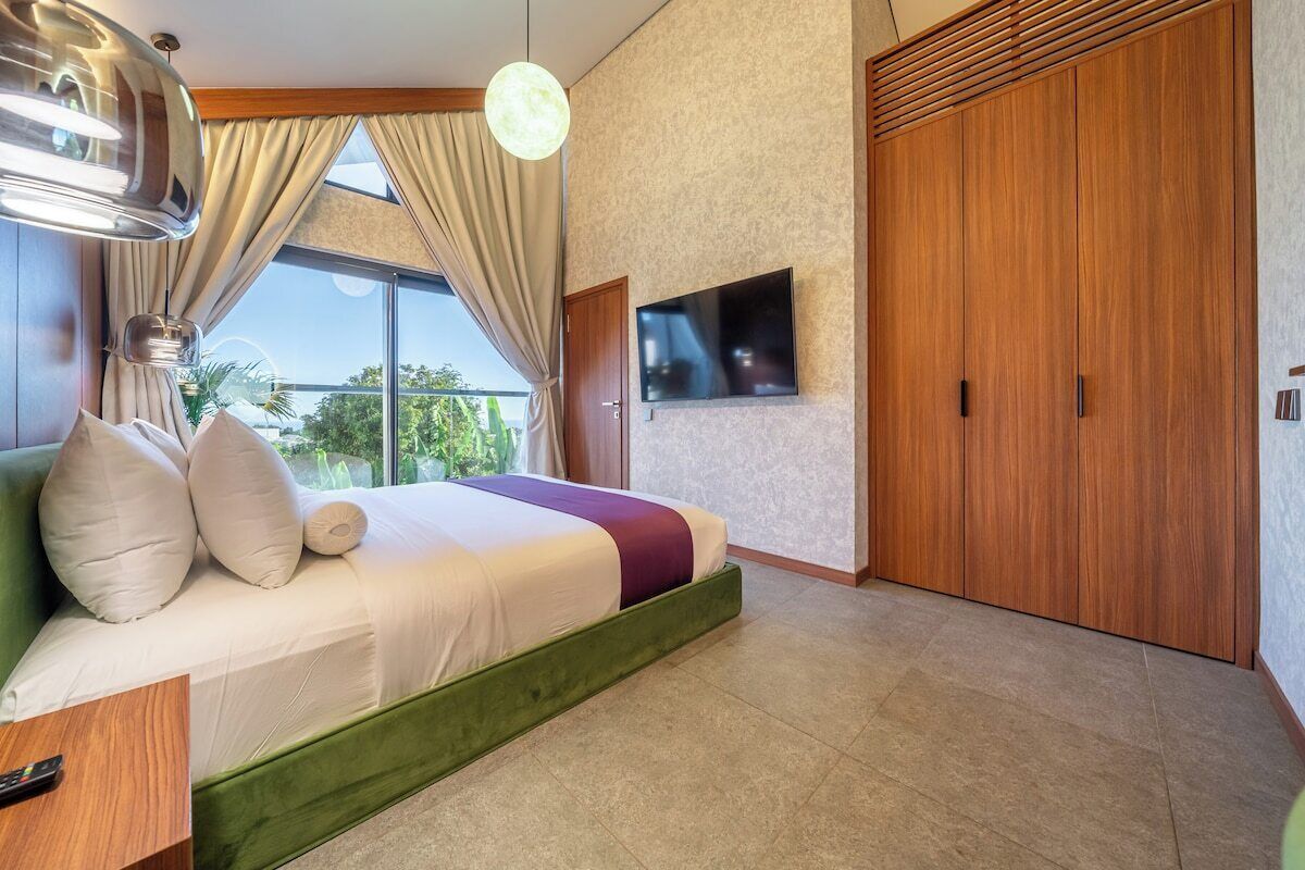 Une chambre à coucher moderne avec un lit, des rideaux, un téléviseur et une armoire.