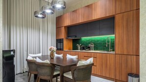 Una cocina moderna con armarios de madera, una mesa de comedor con sillas y un salpicadero verde.