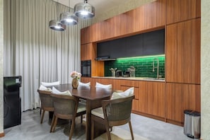 Une cuisine moderne avec des meubles de rangement en bois, une table à manger avec des chaises et un revêtement mural vert.