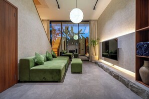 A modern living room with a sofa set, a flat-screen TV, and a large window with a view. - U Vulla 12 - Modern 2BR Villa w Beach Nearby & Private Pool (Badung Regency)