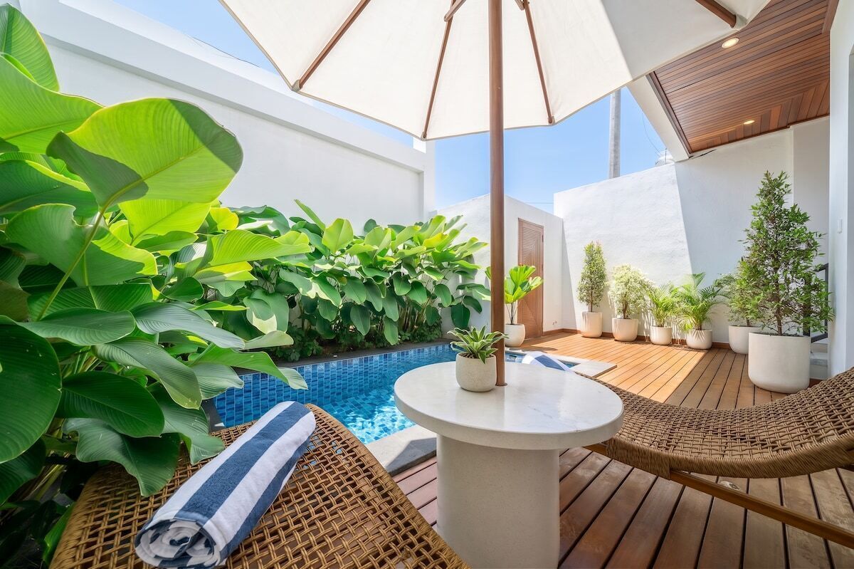 A rooftop terrace with a pool, wicker furniture, and potted plants.