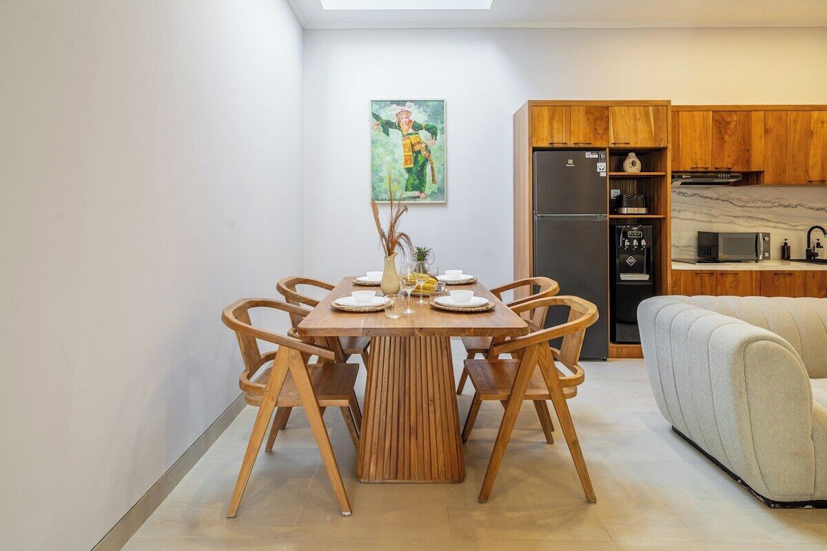 A dining area with a wooden table and chairs, a kitchen with wooden cabinets, and a sofa.