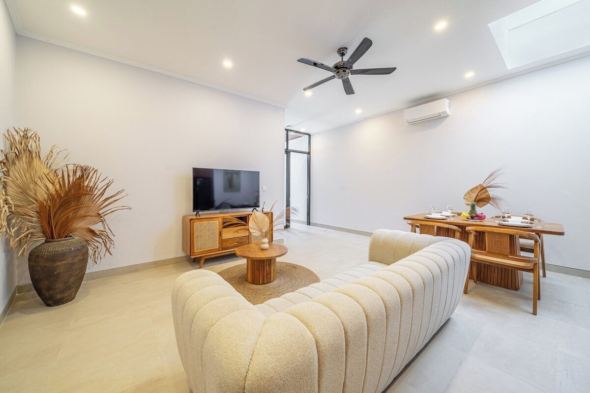 Ein modernes Wohnzimmer mit einer Couch, einem Fernseher und einem Essbereich.