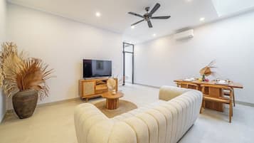 Ein modernes Wohnzimmer mit einer Couch, einem Fernseher und einem Essbereich.