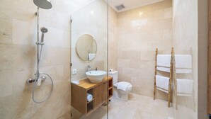 A modern bathroom with a glass-enclosed shower, a wooden vanity, a round mirror, and a bamboo towel rack. - Designer 3BR Villa by Sanur Beach • Pool & Rooftop (Denpasar Selatan)