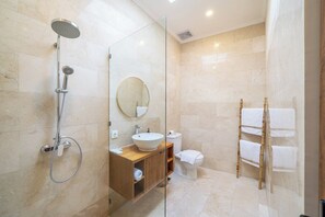 A modern bathroom with a glass-enclosed shower, a wooden vanity, a round mirror, and a bamboo towel rack. - Designer 3BR Villa by Sanur Beach • Pool & Rooftop (Denpasar Selatan)