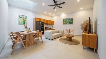 A modern interior with a dining area, sofa, and a ceiling fan.