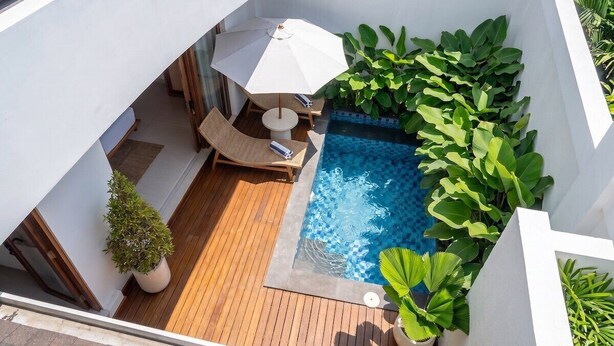 A rooftop pool area with a wooden deck, a lounge chair, a small table, and a white umbrella. - Designer 3BR Villa by Sanur Beach • Pool & Rooftop (Denpasar Selatan)