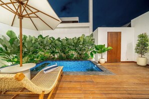 A pool area with a wooden deck, a lounge chair, and a large umbrella. - Designer 3BR Villa by Sanur Beach • Pool & Rooftop (Denpasar Selatan)