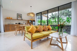 Ein modernes Wohnzimmer mit einer Couch, einem Couchtisch und einem Essbereich mit Stühlen.