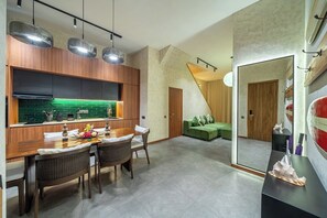 Eine moderne Küche mit Essbereich, einem grünen Sofa und einem Spiegel, der den Raum reflektiert.