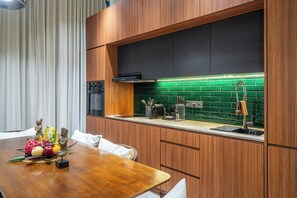 Cozinha moderna com armários de madeira, coifa preta e painel de parede verde.