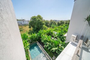 Ein Pool auf dem Dach mit umliegender Bepflanzung und Blick auf entfernte Gebäude.