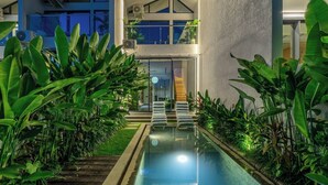 Et moderne hus med swimmingpool, omgivet af frodig vegetation.
