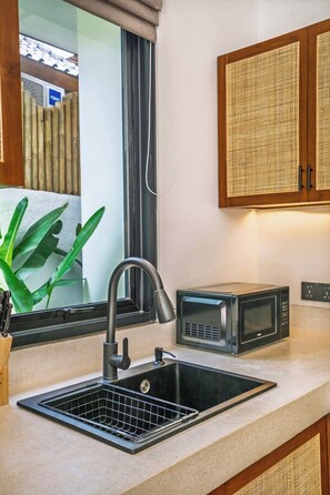 A kitchen with a black sink, a microwave, and a window with a curtain. - Tropical 2BR Gem in Ubud w Private Pool & Gazebo (Gianyar Regency)