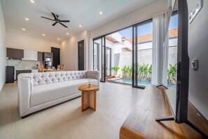 Ein modernes Wohnzimmer mit einer Couch, einem runden Holztisch und einem Deckenventilator.