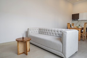 Ein Wohnzimmer mit einer Couch, einem kleinen runden Tisch und einem Essbereich mit Stühlen und gedecktem Tisch.