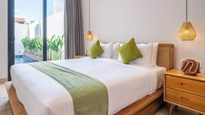 Hotellihuone, jossa on suuri sänky, yöpöytä, yövalaisin ja näkymä uima-allasalueelle.