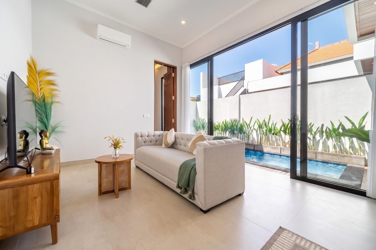 A modern living room with a sofa, a TV, and a small table with decorative items.
