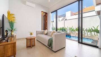 A modern living room with a sofa, a TV, and a small table with decorative items.