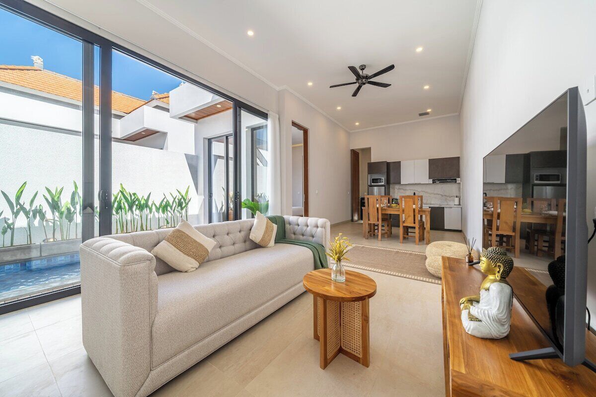 A modern living room with a sofa, coffee table, and a Buddha statue.