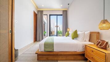 A modern bedroom with a large bed, wooden nightstand, and a view through a sliding door to an outdoor balcony.