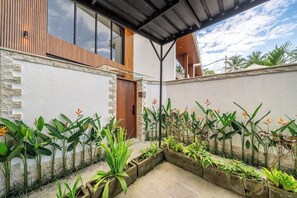 A modern house with a covered patio, stone walls, and a variety of tropical plants. - Cozy 1BR Gem in Ubud w Pool • Perfect for Couples! (Kabupaten Gianyar)