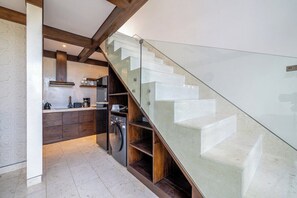 A modern kitchen with a glass staircase leading to an upper level. - Cozy 1BR Gem in Ubud w Pool • Perfect for Couples! (Kabupaten Gianyar)