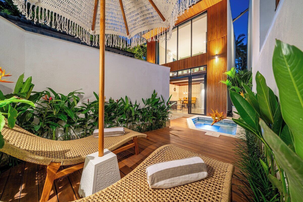 Ein moderner Außenbereich zum Entspannen mit Holzboden, Korlounge-Sesseln und einem Pool.