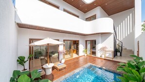 Ett modernt hus i två våningar med en swimmingpool, utomhusmöbler och en trappa.