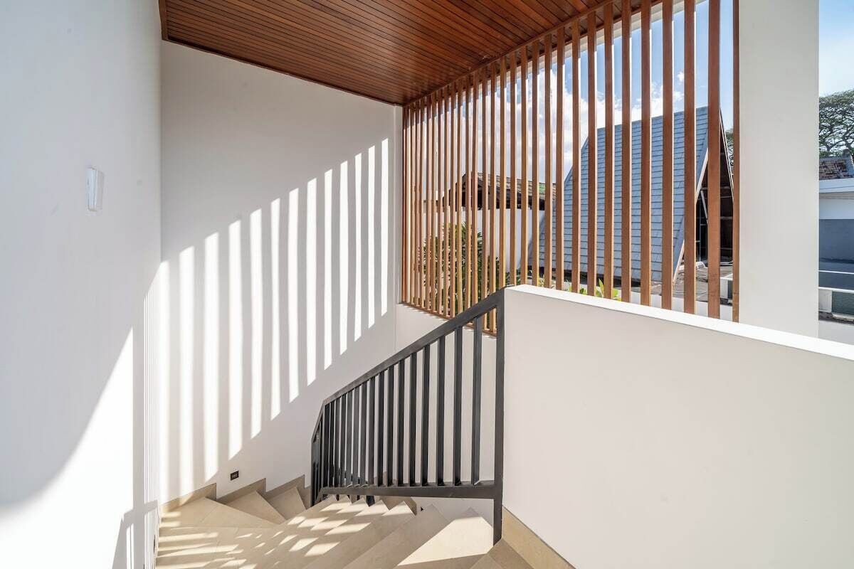 A staircase with a wooden railing and a view of a building outside.