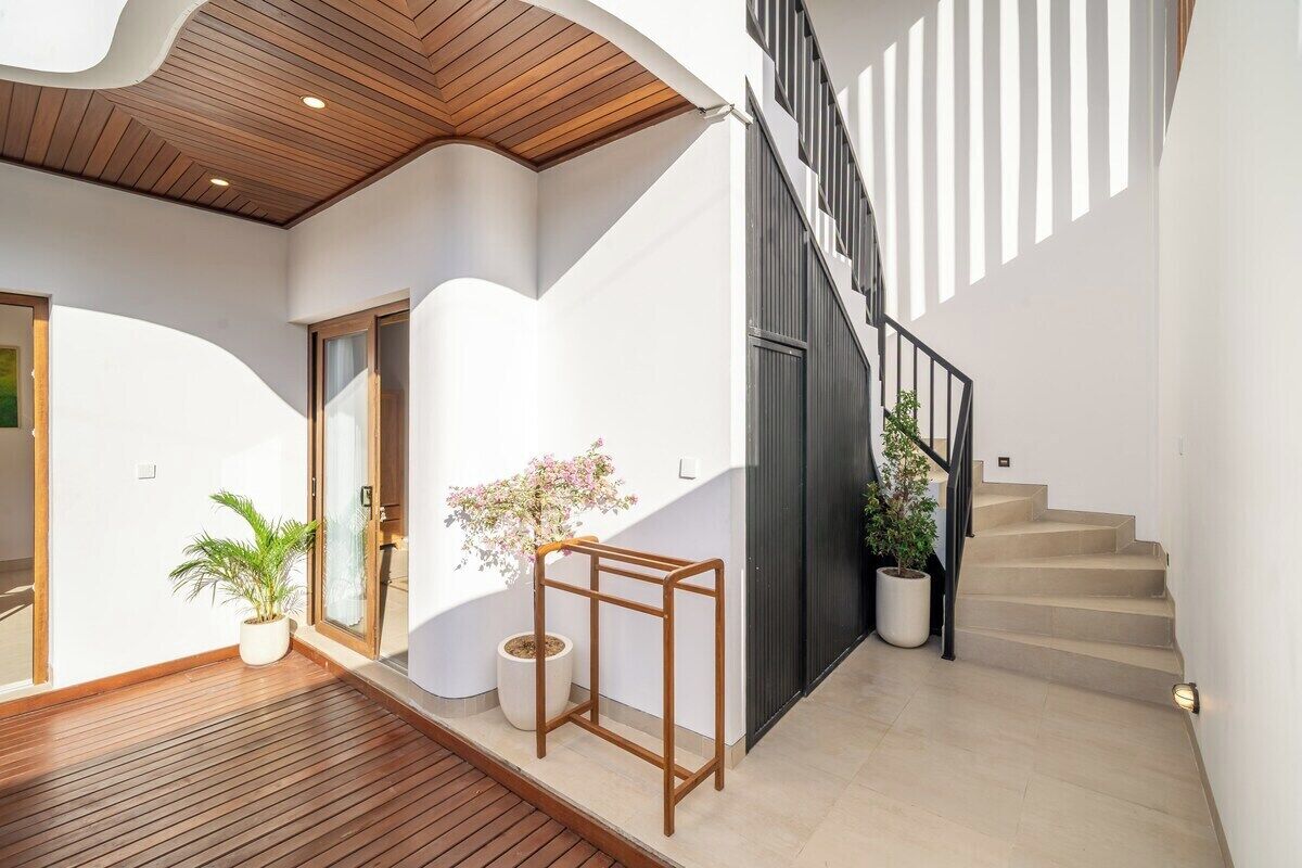 A modern interior with a wooden ceiling, a staircase, and potted plants.
