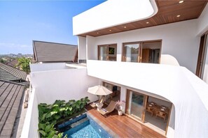 Een modern woongebouw met een zwembad op het dak, een balkon met zitplaatsen en uitzicht op de omgeving.