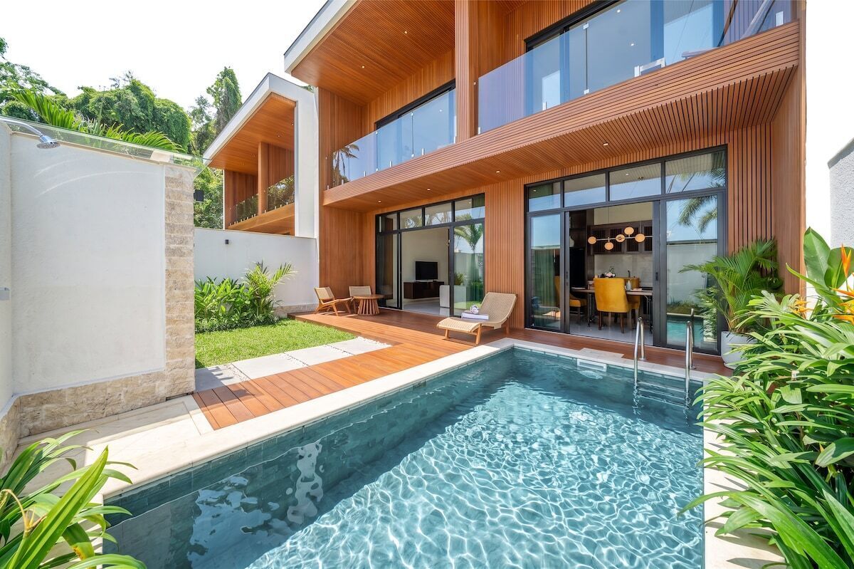 Ein modernes Haus mit Schwimmbad, Holzterrasse und Sitzgelegenheit im Freien.