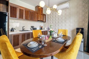 A modern kitchen with wooden cabinets, a dining table set for four, and a decorative light fixture above. - Spacious 2BR Villa w Pool, Garden & Balcony • Ubud (Kabupaten Gianyar)