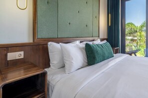 A hotel room with a bed, a nightstand, a green headboard, and a window with a view of greenery. - Spacious 2BR Villa w Pool, Garden & Balcony • Ubud (Kabupaten Gianyar)