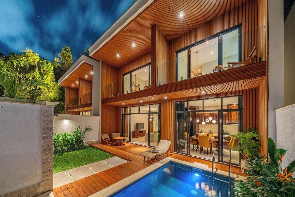 Una casa moderna con piscina, fachada de madera y zona de comedor con mobiliario exterior.