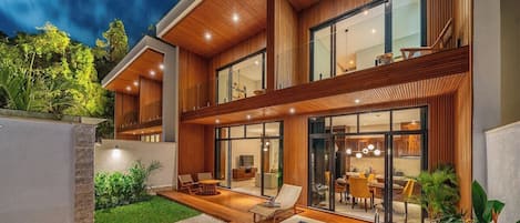 Una casa moderna con piscina, fachada de madera y zona de comedor con mobiliario exterior.