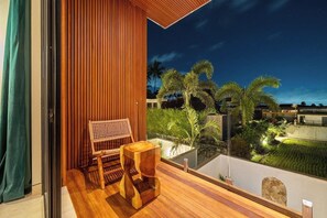 A balcony with a wooden floor, a woven chair, and a small wooden table. - Spacious 2BR Villa w Pool, Garden & Balcony • Ubud (Kabupaten Gianyar)