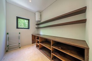 A room with a built-in wooden shelf unit, a radiator, and a window with a view of greenery. - Tropical 2BR in Ubud w Pool, Huge Garden & Balcony (Ubud)