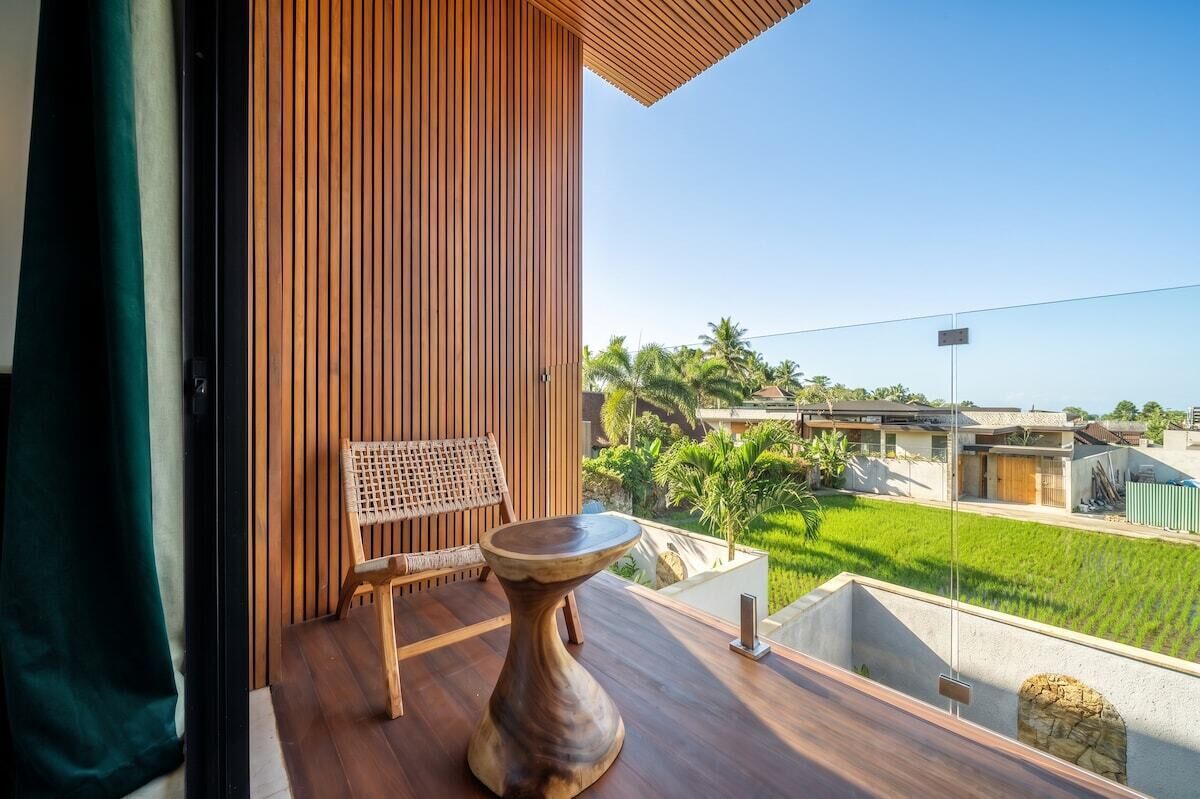 A balcony with a wooden floor, a woven chair, and a wooden table.