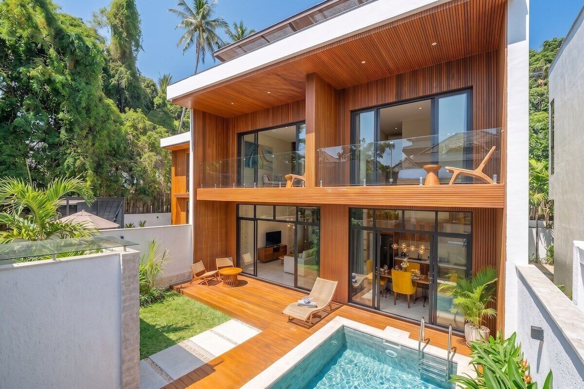 Ein modernes, zweistöckiges Haus mit Schwimmbad, einer Holzterrasse und Glasüren zum Außenbereich.