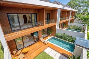 Ein modernes, zweistöckiges Haus mit einem Glasbalkon, einem Schwimmbad und Sitzgelegenheiten im Freien.