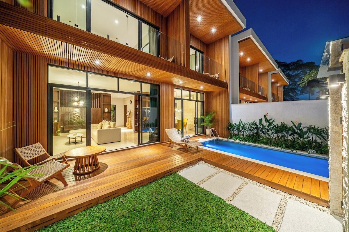 A modern house with a swimming pool, wooden deck, and outdoor seating area.