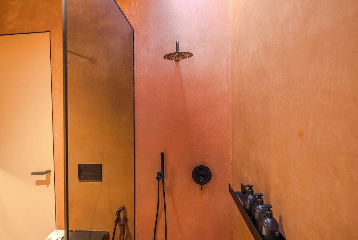 A bathroom with a shower, a towel rack, and a soap dispenser.