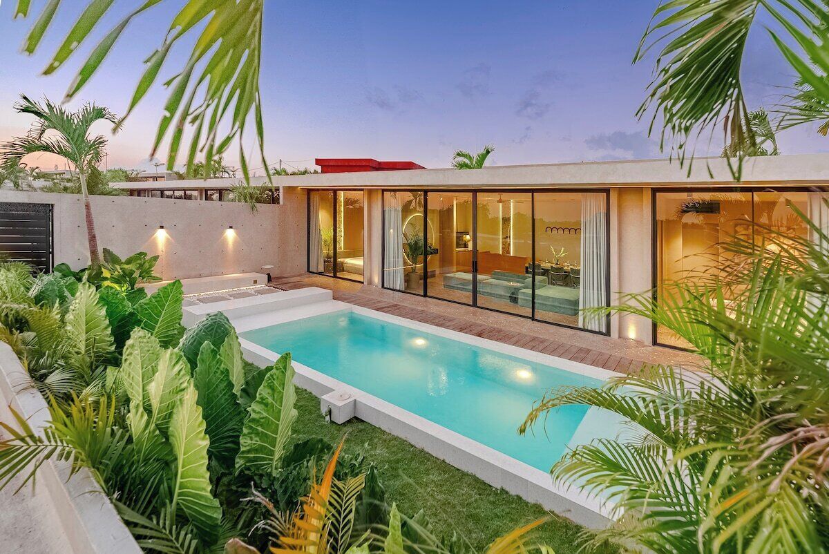 Una casa moderna con piscina, rodeada de abundante vegetación.