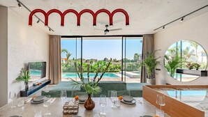 Un espace repas offrant une vue sur une piscine et sur la verdure.