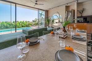 A dining area with a view of a pool and greenery, a round mirror, and a bar area. - Tropical 2BR Villa in Canggu • Beach Nearby • Pool (Kabupaten Tabanan)